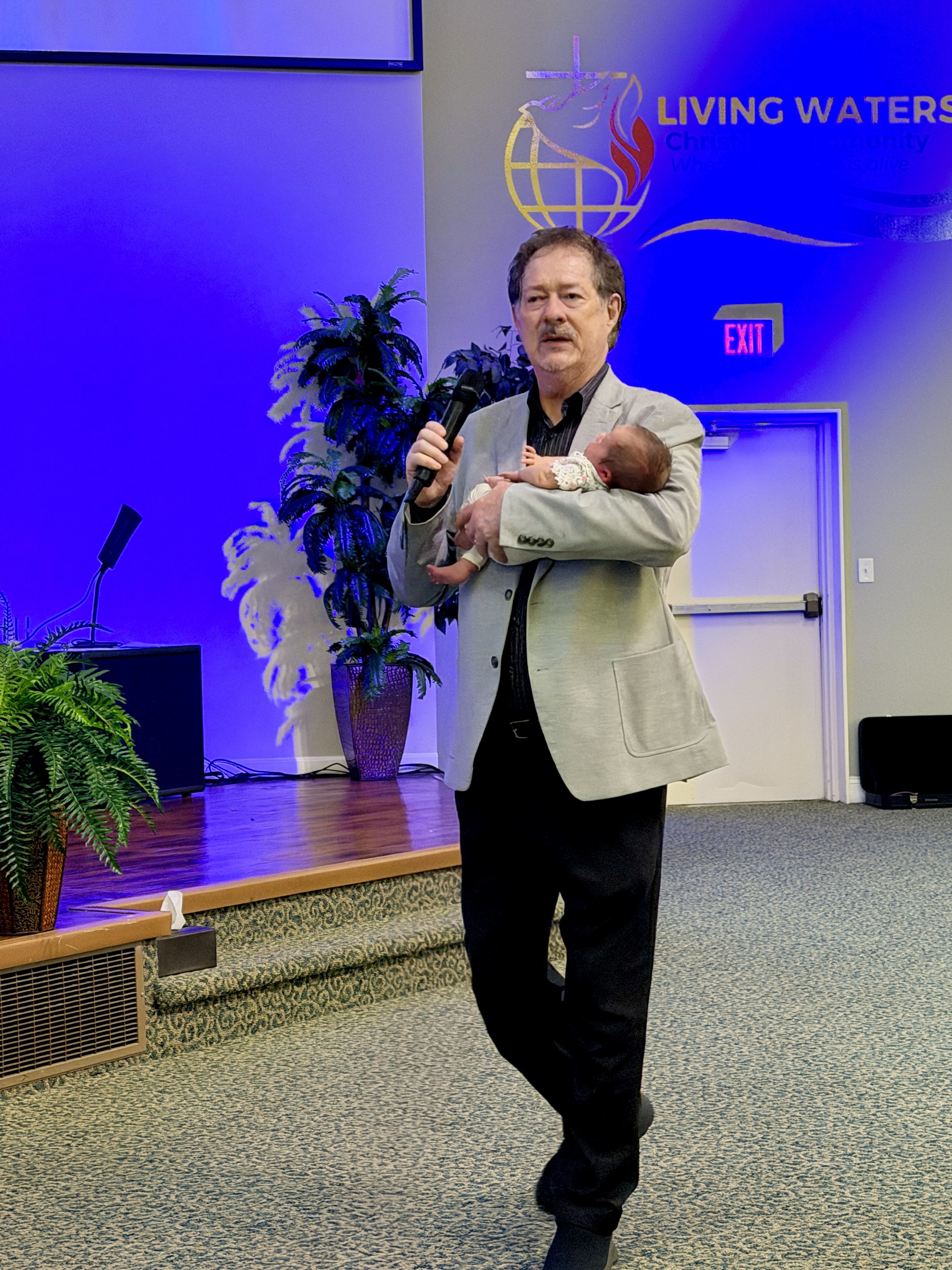 Pastor holding a baby during a service at Living Waters